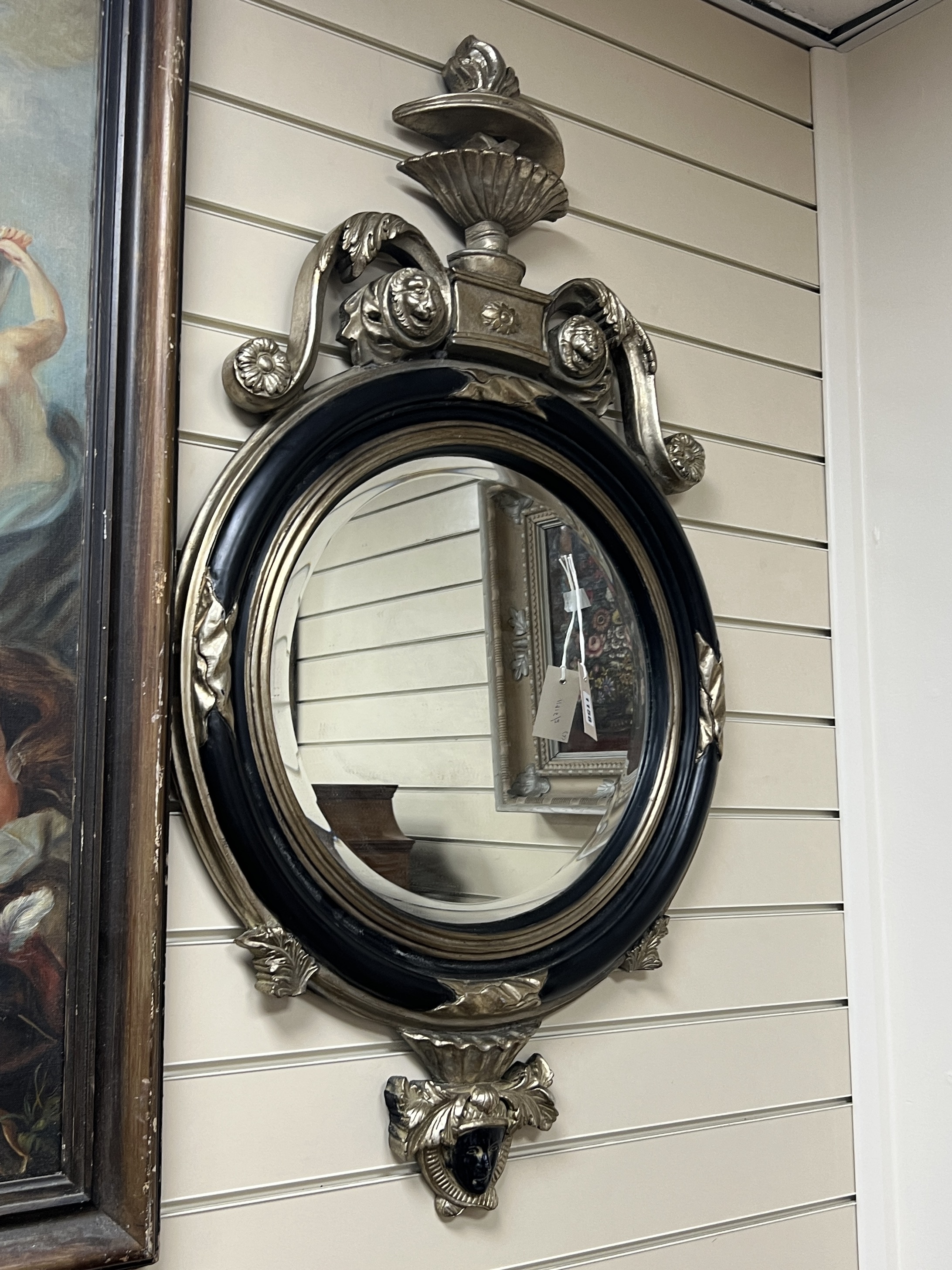 An 18th century style circular wall mirror with vase pediment, width 60cm, height 104cm together with an oval floral moulded wall mirror